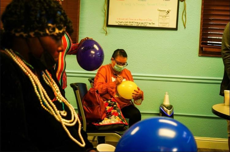 Mona Debbs and Emily Saso write messages on balloons